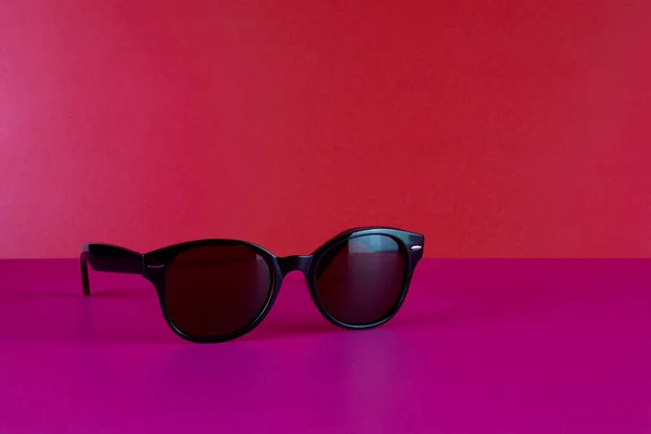 Designer Sonnenbrille Auf Rosa Tischplatte Mit Rotem Hintergrund — Stockfoto