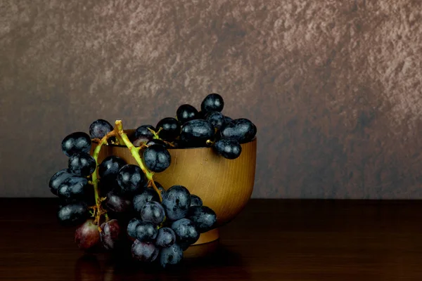 磨かれた木のテーブルの上のブドウの束が付いている小さい木製のボール — ストック写真