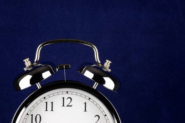 Geleneksel çalar saatin kısmi görünümü ve mavi arkaplanda çanlar