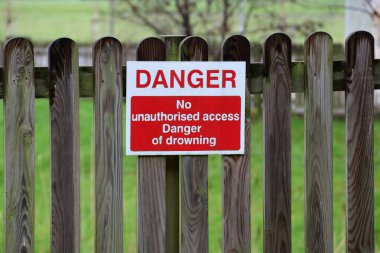 Danger No Unauthorised Access Danger of Drowning signage at an urban public park clipart