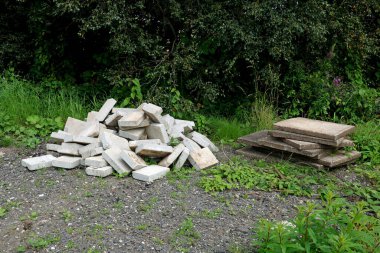 Kırsal bir çiftlikte eski kaldırım levhaları ve beton bloklar bir araya toplanmış.