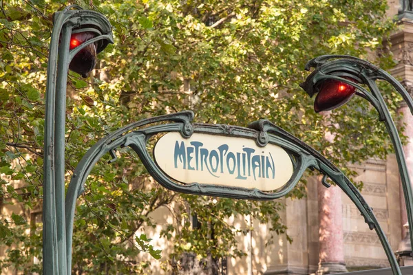 Paris, Fransa. Ağustos 2022. Paris metro ağının sarı retro tarzı Metropolitain tabelası yapraklı yeşil ağaçlara karşı. Yüksek kalite fotoğraf