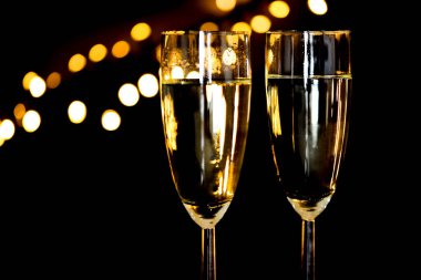 Den Helder, Hollanda. Aralık 2022. Bokeh 'li siyah arka planı olan iki kadeh şampanya. Yüksek kalite fotoğraf
