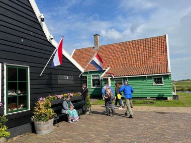 Zaandam, Hollanda. 30 Nisan 2024. Zaanse Schans 'taki turistler. Tipik Hollandalı: tahta ayakkabılar, laleler ve yel değirmenleri. Yüksek kalite fotoğraf