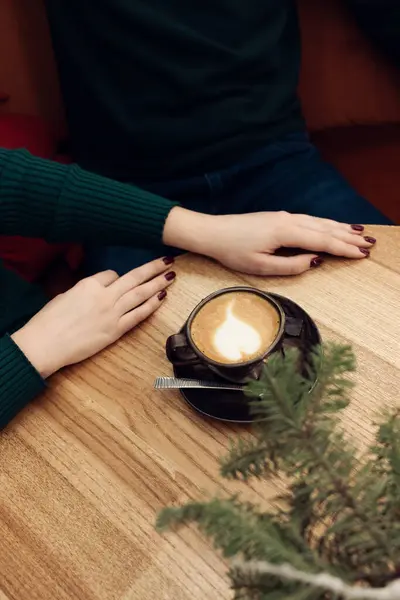 Bir fincan kapuçino ve noel ağacıyla genç bir kadın.