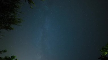 Geceleyin yıldızlar sönüyor ve Samanyolu zeytin ve portakal ağaçlarının arkasına geçiyor. Mavi gökyüzü ve yıldızlı gece manzarası.