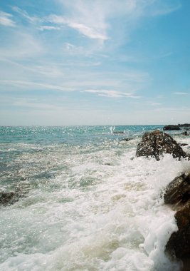 Büyük kayalar ve dalgalarla deniz manzarası. Deniz suyu kayalara sıçrar Açık bir günde güzel bir sahil manzarası