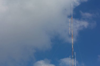 Gökyüzü arka planı parlak kırmızı-beyaz bir anten ve bölgeye yakın uçan bir kuş..