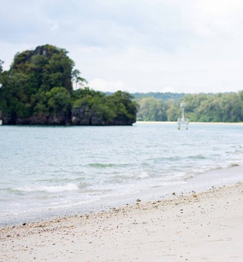 Kum sahil suyundaki deniz dalgaları ve sahil manzarası okyanus mavisi gökyüzü ve Tayland yaz tatilinde tatil beldesi olan tropik deniz manzarası.