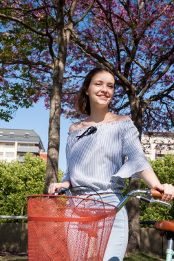 Charming young woman, Caucasian, short hair, next to a bicycle outdoors