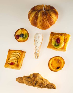 İki kek. Biri meyveli, biri beyaz arka planda kremalı.