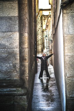 Yağmurlu bir şehirde dar bir caddenin ortasında bir kadın.