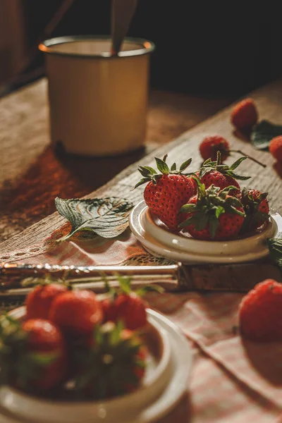 stock image Small containers on a quality wooden table with strawberries inside and outside with a knife and a jar with a spoon