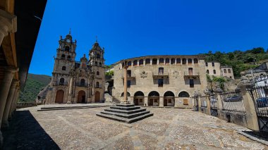 Çan kuleleri ve önünde bir meydan olan taş kilise kaldırımlı ve diğer manastır yapıları