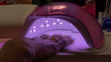 Tırnakların boyandığı cilayı tamir etmek için bir makineye yerleştirilmiş.