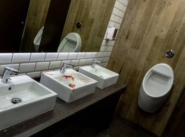 Kişisel el hijyeni için umumi alan. Lavabolardan birinin kırıldığı aynalı.