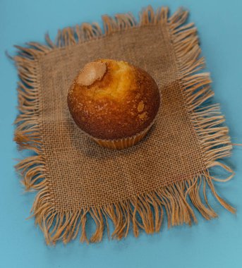 Baked cupcake placed on a rustic napkin on a bluish background clipart
