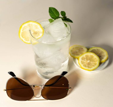 Güneş gözlüklü ve limonlu sıvının düşük sıcaklığı nedeniyle camı buğulandıran su dolu bardaklar.