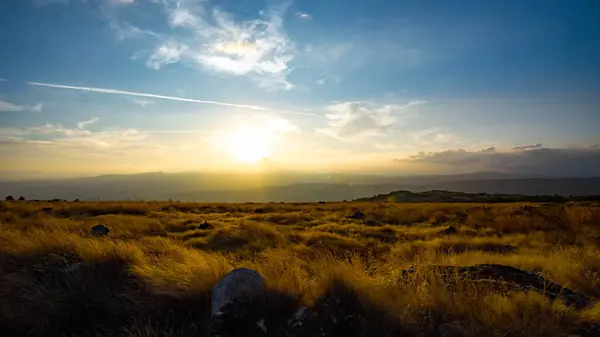 stock image sunset in a high place where you can see the horizon with the sun setting with a field of grass dried by the summer heat