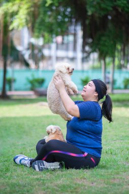 Genç Çinli kadın açık havada parkın manzarasında ve köpek tutuyor.