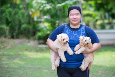 Genç Çinli kadın açık havada parkın manzarasında ve köpek tutuyor.