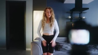 Sosyal medya platformunda beğeniler ve takipçiler için moda dans yarışması videosu kaydeden kız. Komik dans eden bir kadın, ev stüdyosundaki oturma odasında öyküler için performansını filme alıyor..