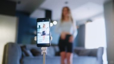 Sarışın kız sosyal medya platformunda beğeniler ve takipçiler için moda dans yarışması videosu kaydediyor. Komik dans eden bir kadın, bir stüdyoda akıllı telefon kamerasıyla kendi performansını filme alıyor..