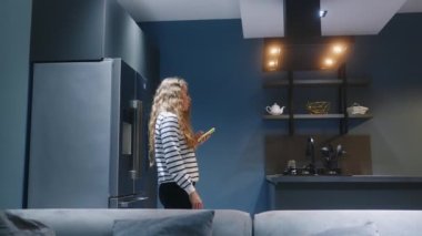 Kadın, oturma odasındaki yıldırım senaryolarını kontrol etmek ve şarap dökmek için telefonda uygulama kullanıyor. Kadın mutfağa giriyor, akıllı ev bilgisayarındaki akıllı telefon uygulaması ile ışıkları açıyor. Nesnelerin interneti
