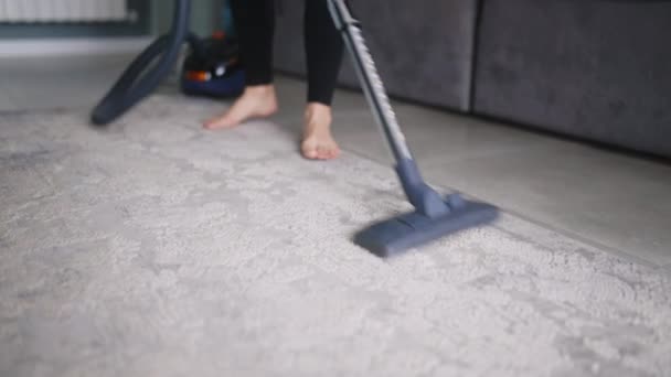 掃除機付きのアパートで床を掃除している女性の低角度ショット 大人の女性はスタイリッシュなアパートでラグをきれいにします 家を掃除するプロセス 主婦は部屋の混乱を片付けた — ストック動画