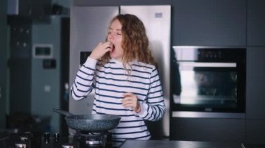 Kadın tavadan sağlıksız kızarmış yiyecekler yiyor, mutfakta şiddetli karın ağrısı çekiyor. Dişi, kızartılmış atıştırmaya çalışıyor, çok hasta hissediyor. Keskin gastrit, ülser ve karaciğer ağrısı çeken bir kız..