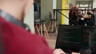 Laptop klavyesinde yazı yazan serbest yazar birlikte çalışma masasında oturuyor. Kamera geliştiricinin etrafında uçuyor ve ofiste bilgisayar ekranında program kodları yazıyor. Çevrimiçi uygulama üzerinde çalışan programcı