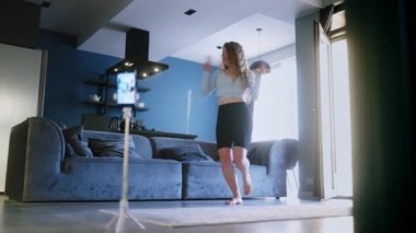 Genç kız, sosyal medya platformunda beğeniler ve takipçiler için moda dans yarışması videosu kaydediyor. Komik dans eden bir kadın, bir stüdyoda akıllı telefon kamerasıyla kendi performansını filme alıyor..