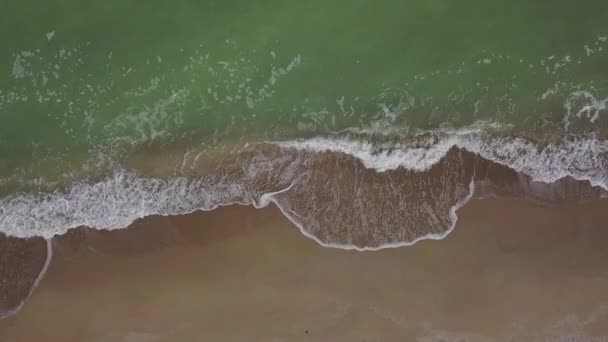 静かな空のビーチ 泡の海の波が海岸に砂を洗うの空中トップダウンビュー 波が石の防波堤と砂浜の海岸線を襲う 上から見ると ドローンは右に動く — ストック動画