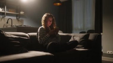 Akıllı telefonları kaydıran, internette sörf yapan gece şık oturma odasındaki kanepede oturan bir kadın. Mobil oyunlar oynayan ya da mağazadan alışveriş yapan bir kadın. Telefonu olan kız sosyal ağlarda sohbet etmekten hoşlanıyor.