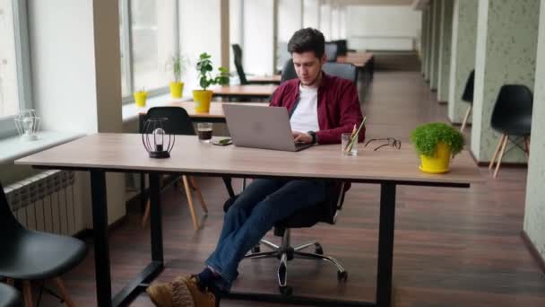 年轻的自由职业者与笔记本电脑在明亮宽敞的合作单独工作 在开放空间办公室工作的创意设计师 开发人员在计算机键盘上打字 穿着格子衬衫的时髦男人 — 图库视频影像