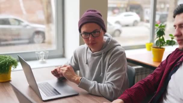 两位嬉皮士同事分享了关于在宽敞的开放办公室里与笔记本电脑一起坐在项目的想法 开发人员讨论软件程序代码 就工作计划进行协商的设计人和管理人 — 图库视频影像
