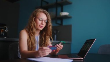 Mutlu bir kadının alışveriş yapması, ödemeyi akıllı telefondan yapması. Kadının kredi kartı, telefonu var. Bilgisayarından online alışveriş yapıyor. Müşteri kızı mobil bankacılık uygulaması kullanıyor..
