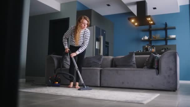 彼女のアパートの若いカクカシア人の女性の真空床 大人の女性は モダンなスタイリッシュなアパートでラグを掃除します 家を掃除するプロセス 部屋の中の混乱を片付ける主婦 — ストック動画