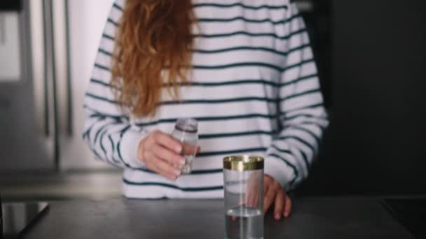 近距离拍摄年轻女子在现代厨房用一杯水吃药的镜头 卷曲的金发女孩每天喝维生素药物是健康的女孩 保健和医药概念 — 图库视频影像