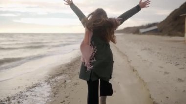 Kumlu deniz sahilinde kaçan oldukça karışık etnik bir kadın. Neşeli, gülümseyen Asyalı, havadar, rüzgarda savrulan bir kadın. Pov, beni takip et. Açık elli kız sahilde eğleniyor. Rüya gibi sinematik slomo..