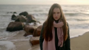 Deniz kıyısında rüya gören üzgün düşünceli kızın portresi. Fırtına sırasında okyanus kıyısında kameraya bakan düşünceli bir kadın. Rüzgârlı dalgalı saçlar. Yavaş çekim rüya gibi sinematik görüntüler.