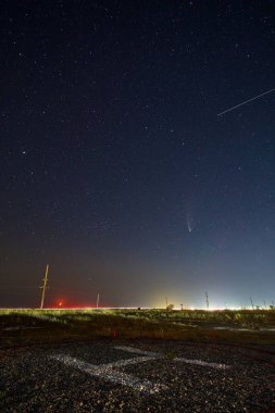 Ay yükselirken Neowise kuyruklu yıldızı C2020 F3 NEOWISE 'nin gerçek yıldızlı fotoğrafı. Helikopter pisti ya da helikopter pisti üzerinde hilal şeklinde yeni ay var. Henychensk, Ukrayna 25 Temmuz 2020.