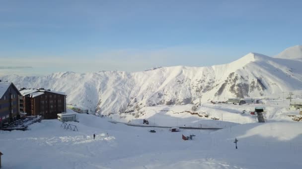 冬季日出背景下 滑雪场 旅舍框架和白雪山岭起重机的施工现场 山脉上覆盖着雪粉 与一座居民楼相映成趣 — 图库视频影像