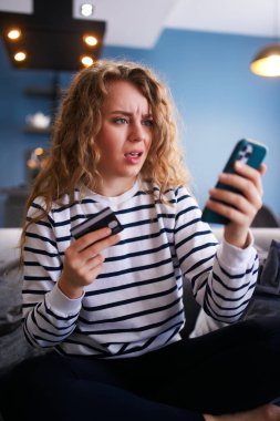 Akıllı telefonu olan endişeli bir kadın, banka kartı faturasını ödemede sorun yaşıyor, banka uygulamasının şifresini unutmuş. Kadın yetersiz fonlar, yaptırımlar ve güvensiz transfer nedeniyle ödeme yapamıyor. Başarısız bir aktarım.