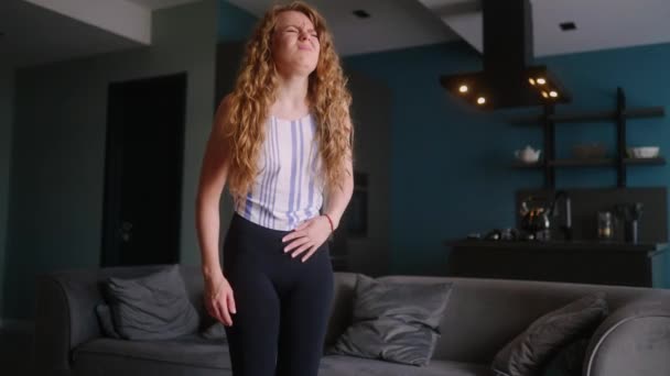 自宅のリビングルームに立って重度の胃の痛みに苦しむ白人女性は 非常に病気を感じている 若い大人の女性は 期間のけいれんを経験する 鋭い膀胱の痛みに苦しんでいる女の子 — ストック動画