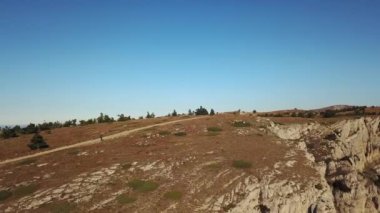 Dağ yolunda yürüyen bir adamın uçan dronundan havadan ateş edildi. Bir uçurumun kenarındaki dağ vadisinde turist yürüyüşü. Dağda yürüyüş turu. Dağ yürüyüşü. 