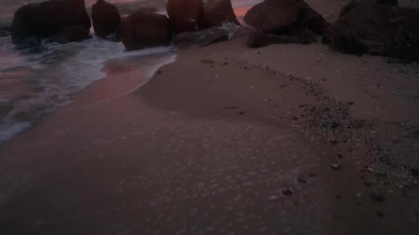 神秘的なヴィンテージは ピンクの夕日の海岸線で海の波に洗われた木の家やチャペルを傾け殺到した 日の出の防波堤の隣の砂浜の水の中に沈む壮大なレンガ造りの建物 — ストック動画