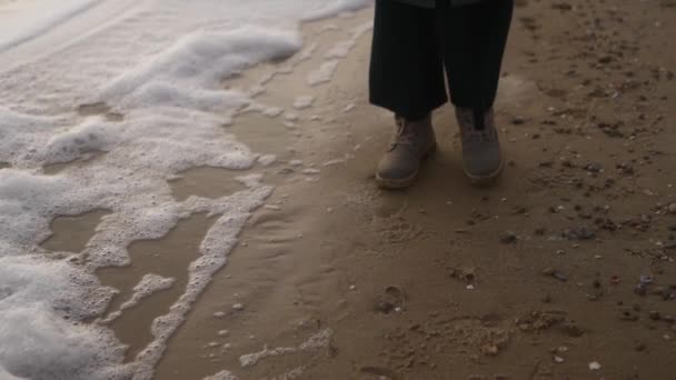 Woman Walks Boots Sea Foam Blown Wind Sandy Beach Slow — Stock Video