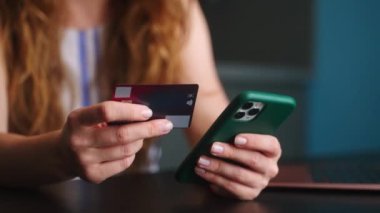 Kadının satın almasına yakın çekim, akıllı telefondan fintech başvurusu ve el işaretini gösteriyor. Kadının kredi kartı, telefonu var, mobil bankacılık uygulaması ile online alışveriş yapıyor..