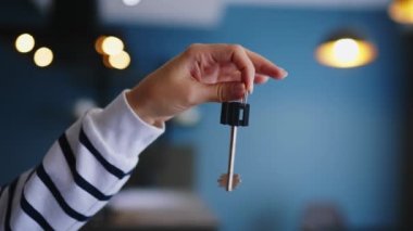 Yeni ev ya da dairenin anahtarını ışık saçan modern iç mekânda gösteren kadın elini kapatıyoruz. Kadın yeni evin anahtarlarını, kirayı veriyor. Emlakçı kiralık daire öneriyor..